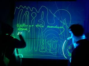 Varias personas dibujan con luz encima de una pintura fotoluminescente
