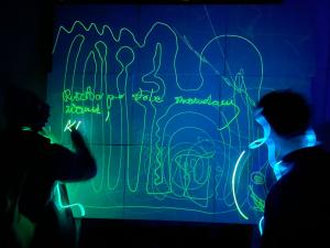 Varias personas dibujan con luz encima de una pintura fotoluminescente